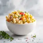 Salade de macaroni servie dans un saladier blanc avec garniture